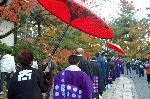 広隆寺　聖徳太子御火焚祭 : 僧侶の列に紅葉の壁に赤い傘